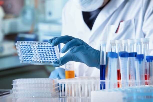 Laboratory technician handling sample plates and test tubes